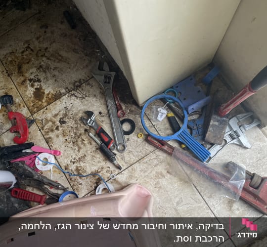 כלי עבודה שונים על רצפה מלוכלכת, כולל מפתח צינורות ומברג.